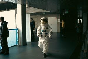 Osoba przebrana za kosmonautę spaceruje po korytarzu.